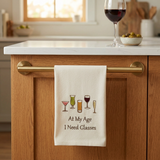At My Age Need Glasses Dishtowel in a cozy home bar setting