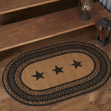 Blackstone Farm Star braided oval rug in black and tan jute — lifestyle view showing scale in a country-style room at base of wood staircase
