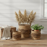Brinkley Rattan Round Baskets Set of 3 — lifestyle view with throw blanket, fall florals and woven rug, all three sizes on hardwood floor