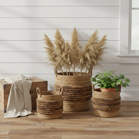 Brinkley Rattan Round Baskets Set of 3 — lifestyle farmhouse view with throw blanket, florals and plant, all three sizes on hardwood floor