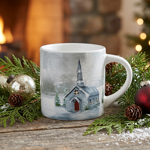 Square Christmas lifestyle image of the Evergreen Church Mug on rustic wood with pine branches, pinecones, ornaments, and warm fireplace light
