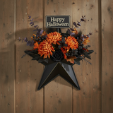 Faceted metal star wall hanging on wood door with Halloween florals and Happy Halloween pick