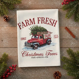A white flour sack tea towel with a vintage-style graphic of a red pickup truck carrying a Christmas tree, with the text 'FARM FRESH', '1982', 'Christmas Trees', and 'PINE • SPRUCE • FIR'.