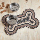 Farmstead Charcoal Dog Bone Braided Rug Mat on pine wood floor with stainless dog bowls, dog bone treats, and asphalt bleached white grey taupe braided detail