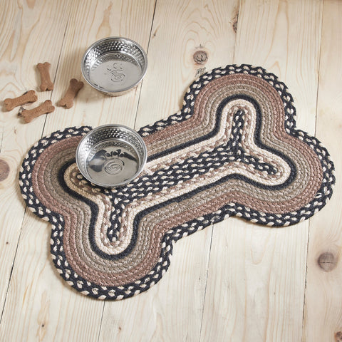 Farmstead Charcoal Dog Bone Braided Rug Mat styled on light wood floor with two stainless steel dog bowls and scattered dog treats