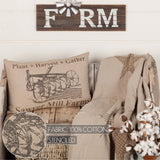 Farmstead Charcoal Plow Harvest Throw Pillow on rustic wood armchair with linen throw and cotton stems, 100% cotton stenciled fabric callout inset