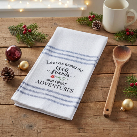 Good Friends Adventure Tea Towel on a wood table with a wooden spoon and Christmas accents