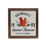 Griswold's Squirrel Removal Holiday Sign 6x6 with a distressed brown wood frame. The sign features a vintage-style illustration of a red squirrel holding a nut with green leaves and red berries, set against an off-white background.