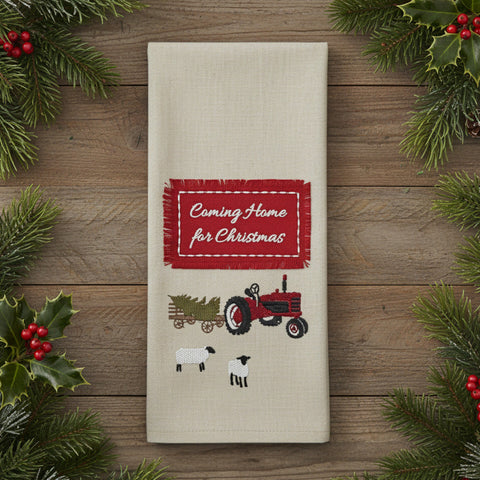 Beige towel with red 'Coming Home for Christmas' label, tractor, and sheep design on a white background