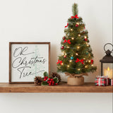 Oh Christmas Tree Holiday Sign 10x10 A small decorated Christmas tree stands on a wooden shelf beside a framed sign reading 'Oh Christmas Tree,' with pinecones, holly, a lantern, and wrapped gifts in a warm holiday setting.