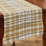 Sage & Mustard Plaid Chindi Table Runners draped over a wooden table, featuring a plaid pattern in sage green, mustard yellow, putty brown and white.