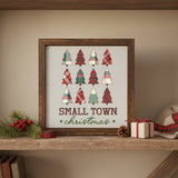 Small Town Christmas wood sign in rustic brown frame displayed on a stone mantel with holly sprigs, red berries, pinecone, plaid tape, and a wrapped gift