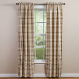 Toffee & Elm Plaid Long Panel Curtains 84" A pair of beige green and brown plaid curtain panels hanging on a black rod over a window, with a light beige wall and a view of greenery outside.